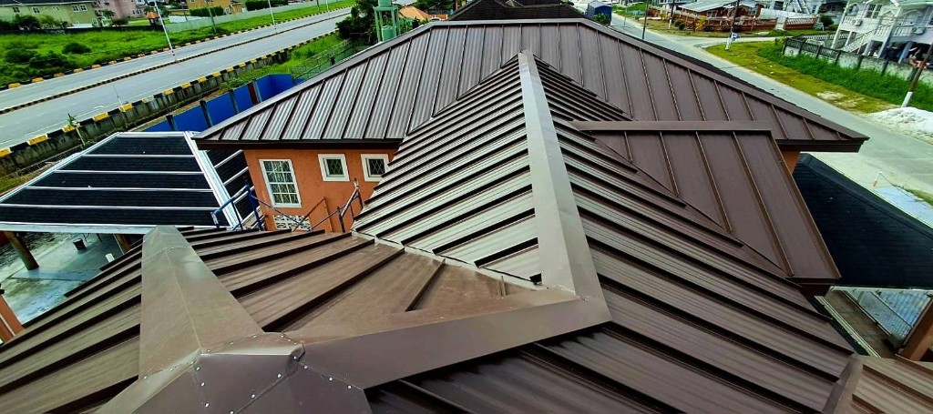 Brown standing seam metal roof with crisp ridges and hips on a home in Georgetown, Guyana