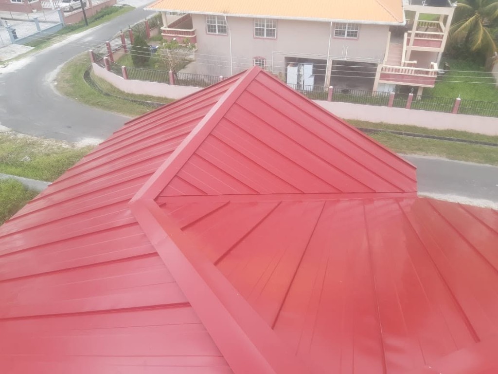 Freshly installed red standing seam metal roof with clean ridge caps